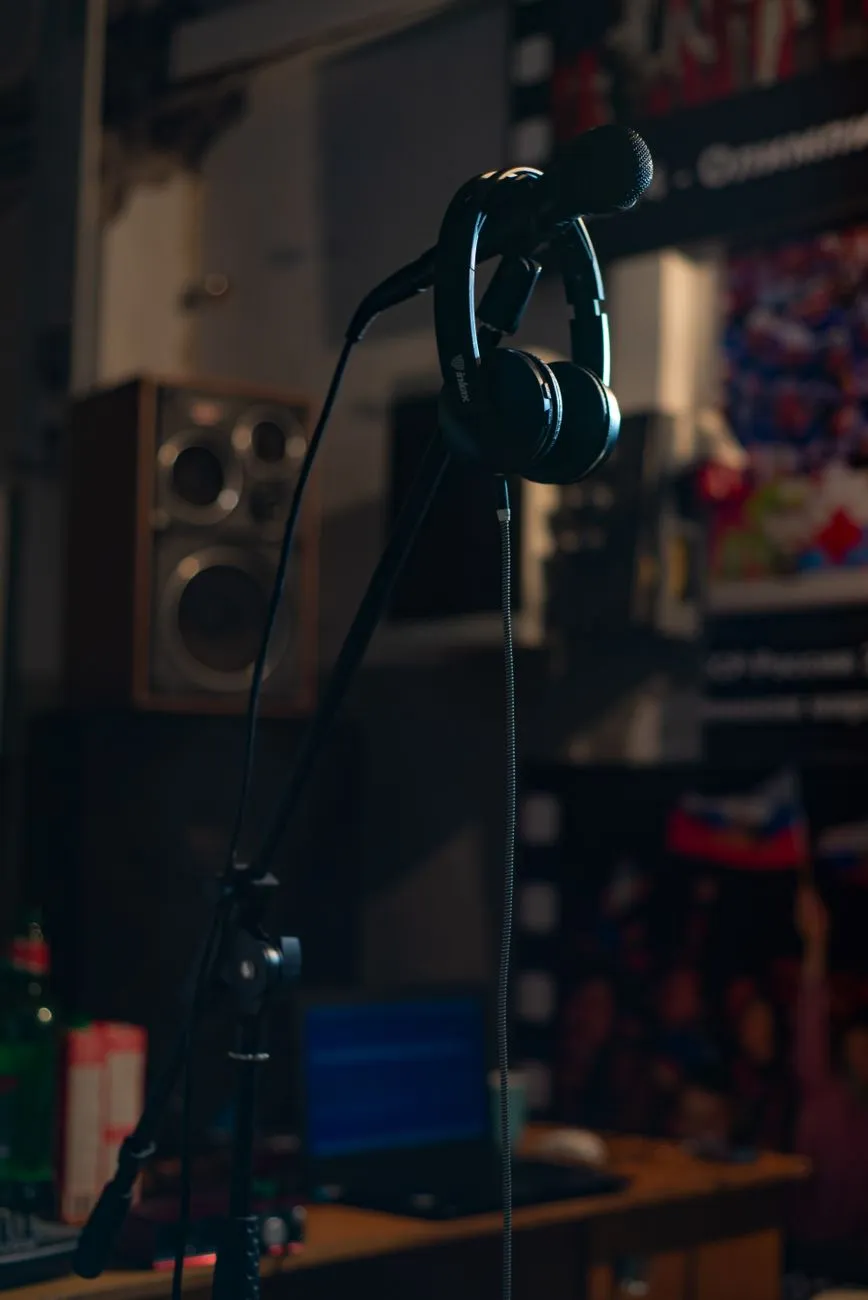 Close up of a microphone stand and headphones in a dimly lit music studio