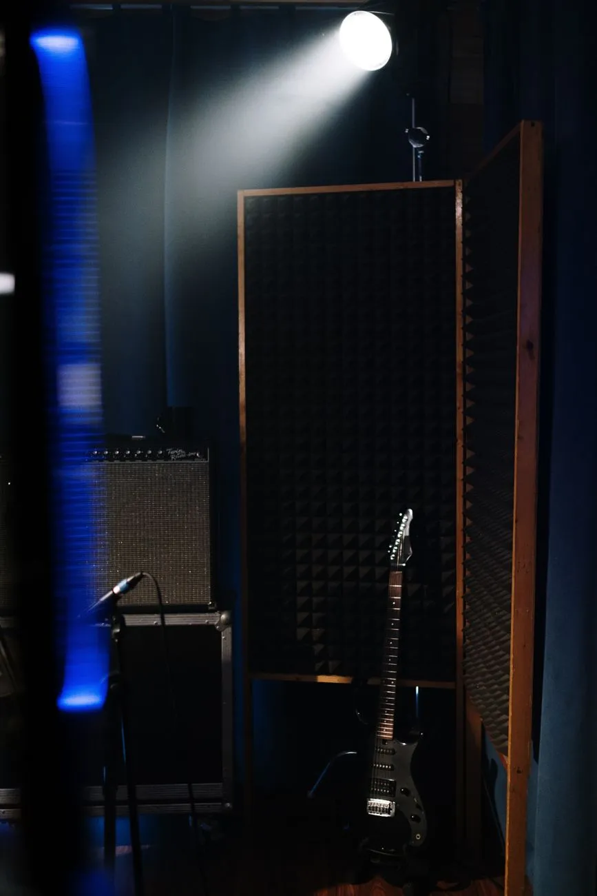 Electric guitar in a dimly lit recording studio with audio equipment