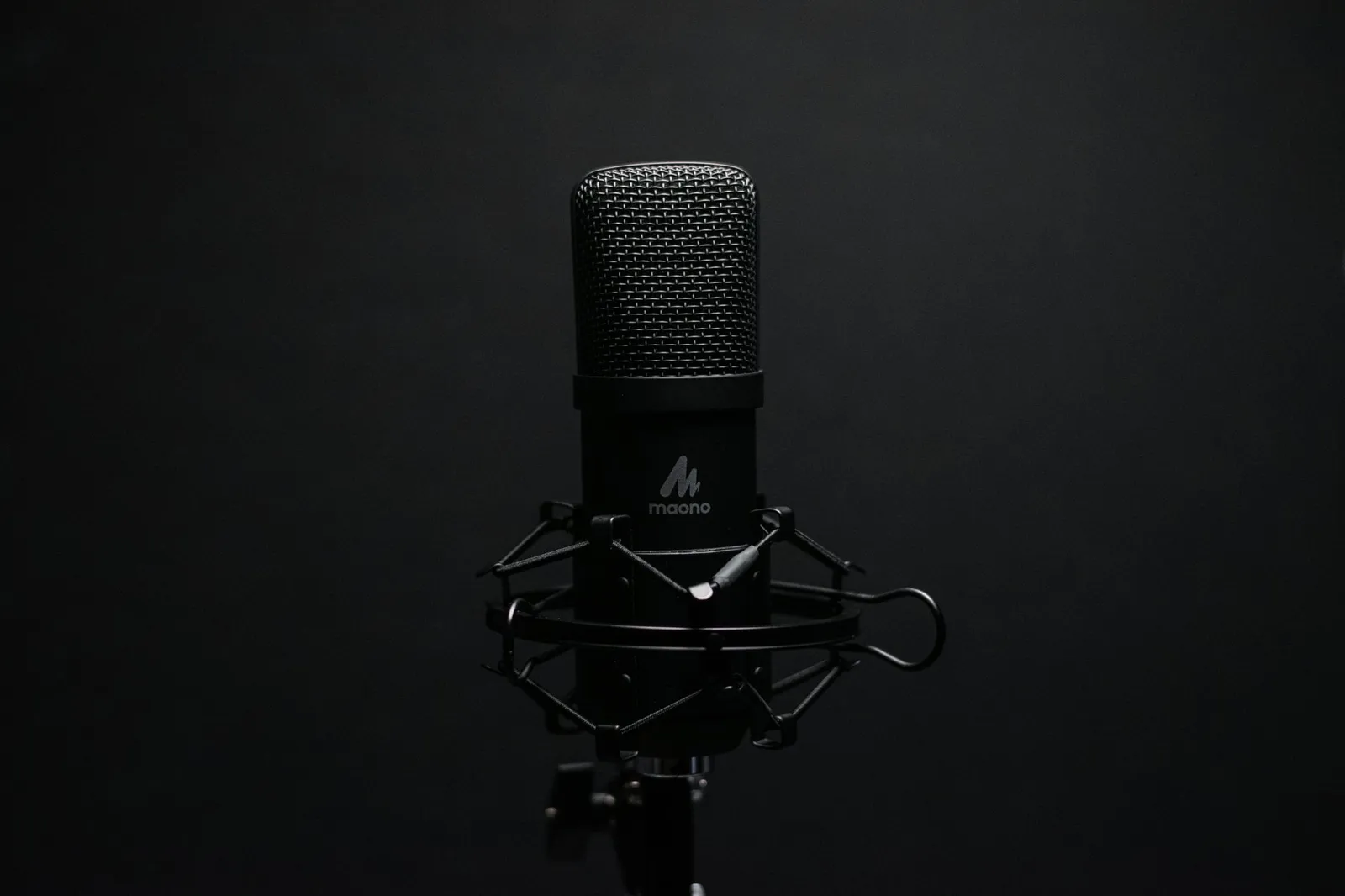 Studio microphone with shock mount on a dark backdrop, perfect for audio recordi