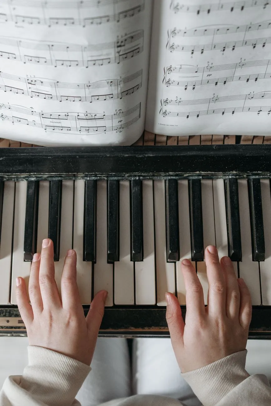 Child playing piano with sheet music above, focusing on hand placement and notes